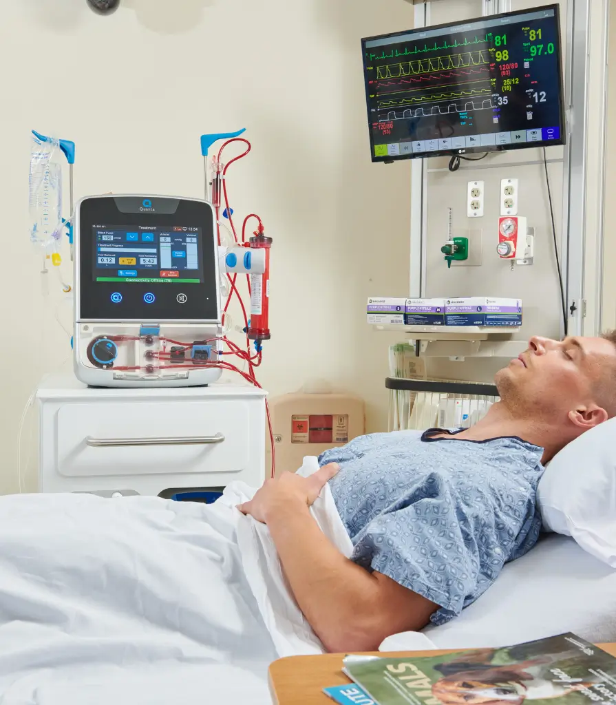 Patient lying in a hospital bed being treated by the Quanta Dialysis system.